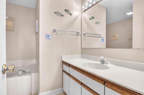 a white bathroom with a sink and a mirror at Sea-Nic View in Caswell Beach