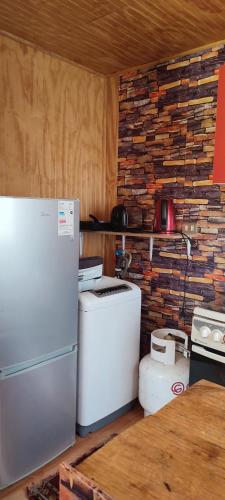 eine Küche mit einem Kühlschrank und einer Ziegelwand in der Unterkunft Cabaña con tinaja El Arrayán in Lago Ranco