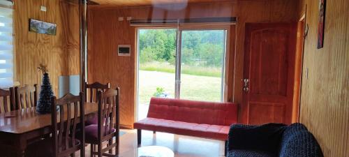 ein Wohnzimmer mit einem roten Sofa und einem Fenster in der Unterkunft Cabaña con tinaja El Arrayán in Lago Ranco