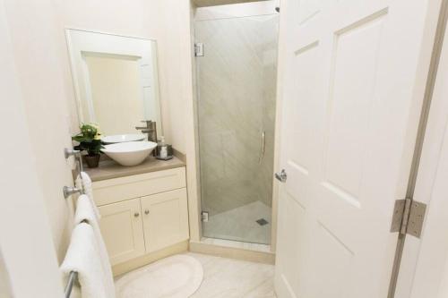 Un baño con ducha, lavabo y espejo. en 102 Lighthouse Bay Barbados, en Christ Church