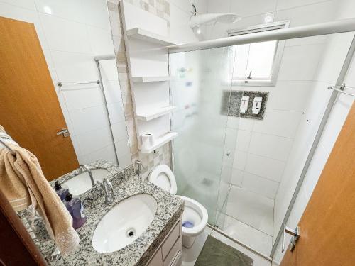 uma casa de banho com um chuveiro, um lavatório e um WC. em 207- APARTAMENTO de 2 QUARTOS no ALTO CAIÇARAS em Patos de Minas