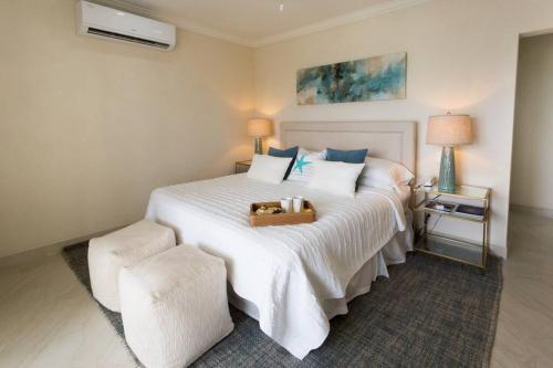 Un dormitorio con una cama blanca con una maleta. en 102 Lighthouse Bay Barbados, en Christ Church