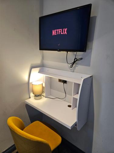 a desk with a monitor and a yellow chair at Tudor Road House in Leicester