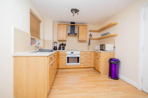 uma cozinha com armários de madeira e um lavatório em Charming 4-bedroom home in Corby em Great Oakley