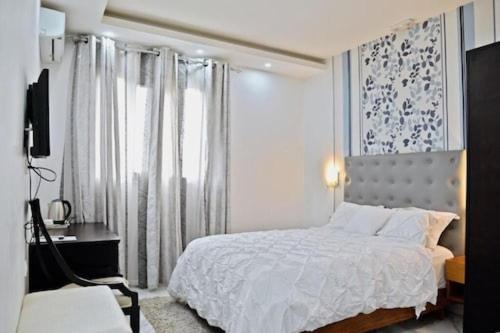 1 dormitorio con cama blanca y ventana en Hôtel Cincinnati, en Yaoundé