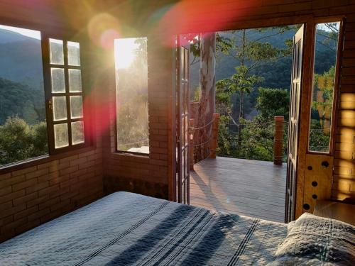 um quarto com uma cama e vista para um deque em Casa Mohini em Teresópolis