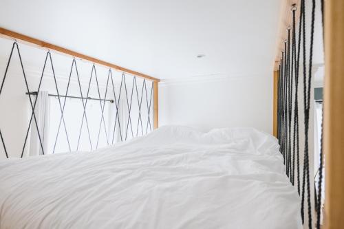 Cette chambre comprend un lit avec des draps blancs. dans l'établissement Studio Vichy célestin Villa Marie Celine, à Vichy