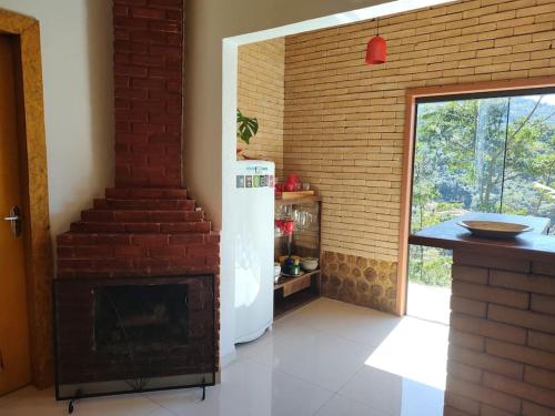 a kitchen with a refrigerator and a brick wall at Casa Mohini in Teresópolis