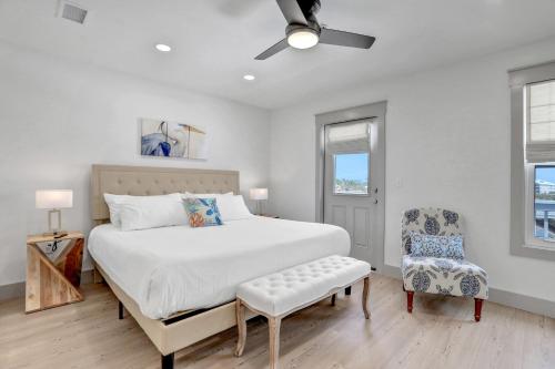 a white bedroom with a bed and a chair at Seaside Harbor Retreat in Mexico Beach