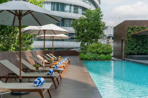 a pool with chairs and umbrellas next to a building at Central Siam Chitlom Superb Luxury 80sqm in Bangkok