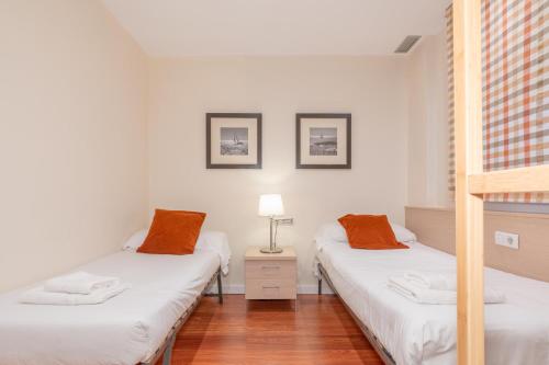 Habitación con 2 camas individuales y paredes blancas. en Serennia Cest Apartamentos Arc de Triomf en Barcelona