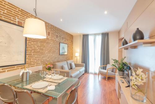 バルセロナにあるSerennia Cest Apartamentos Arc de Triomfのレンガの壁のダイニングルームとリビングルーム