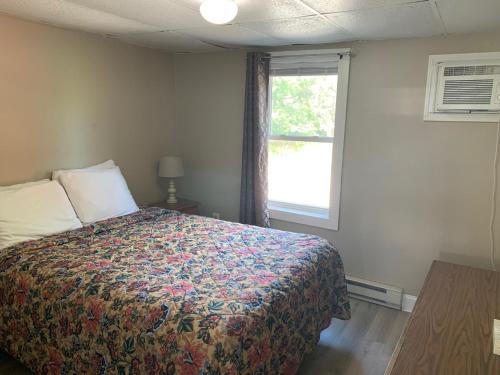 a bedroom with a bed with a colorful blanket and a window at Island View Motel in Old Orchard Beach