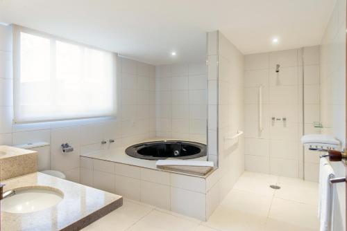 a white bathroom with a sink and a shower at Taiwan Hotel in Ribeirão Preto
