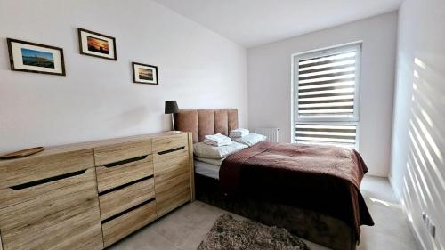 um quarto com uma cama, uma cómoda e uma janela em Kolo Apartament em Koło