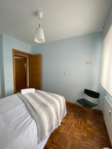 - une chambre avec un lit blanc et une chaise noire dans l'établissement Piso en el centro A Coruña - Cuatro Caminos, à La Corogne