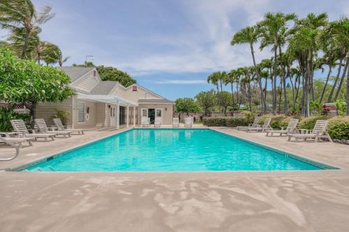 a swimming pool in front of a house with palm trees at Fairway Terrace G101 in Waikoloa Village