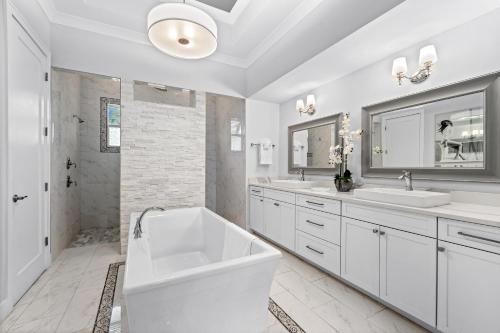 ein weißes Bad mit einer Badewanne, 2 Waschbecken und einer Dusche in der Unterkunft Mi aMora a Bonita Retreat in Bonita Springs