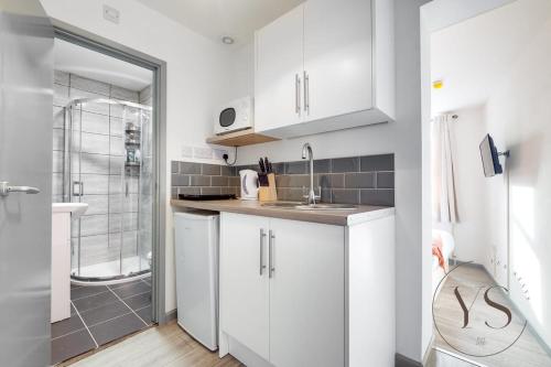 a white kitchen with a sink and a shower at Sienna Studio 1E Near Alton Towers with Free Wi-Fi and Netflix Access in Stoke on Trent