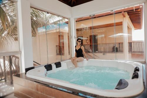 uma mulher sentada numa banheira de hidromassagem numa casa em Pousada Kanto Suites & Spa em Capitólio