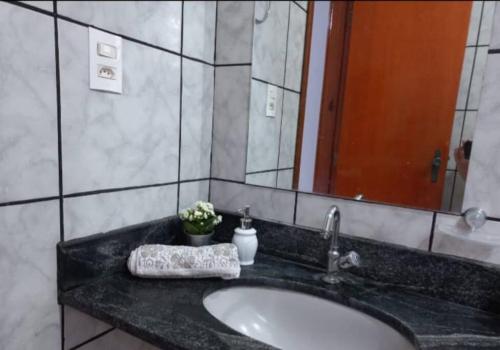 um balcão de casa de banho com um lavatório e um espelho em Casa da Iná! Com piscina e churrasqueira! em Rio Verde