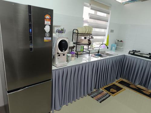 a kitchen with a stainless steel refrigerator next to a sink at JRC Homestay Kerteh in Kemaman