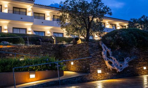 a person sitting on a stone wall in front of a building at Hotel Sol Ixent - Adults Only in Cadaqués