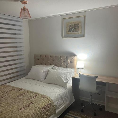 a bedroom with a bed and a desk with a chair at Departamento en Avda. Colón Talcahuano in Talcahuano
