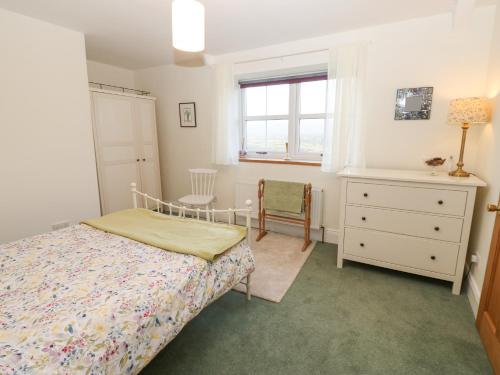 a bedroom with a bed and a dresser and a window at The Byre in Hexham