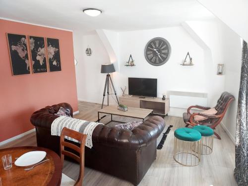 a living room with a leather couch and a clock on the wall at T3 rénové en face des Thermes in Néris-les-Bains