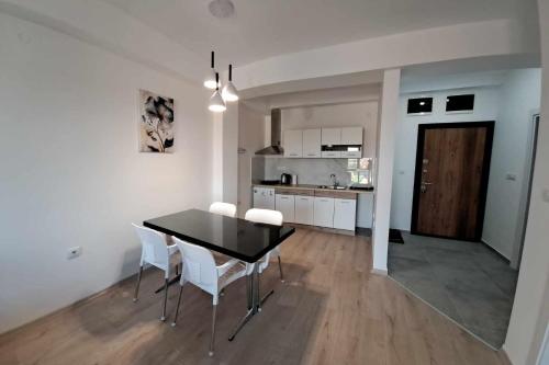 eine Küche und ein Esszimmer mit einem schwarzen Tisch und weißen Stühlen in der Unterkunft Apartment B&S in Skopje