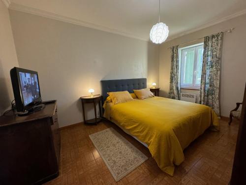FumelにあるChambres d’hôtes de Pouzatelのベッドルーム(黄色いベッド1台、テレビ付)