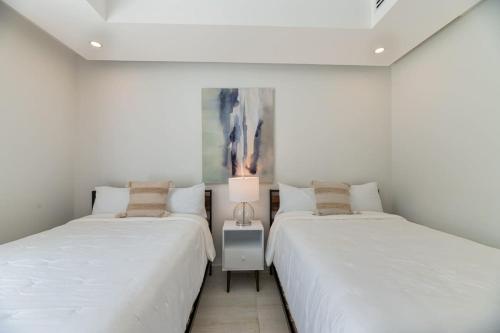 two beds in a room with white walls at Marlin Villa #10 in West Bay