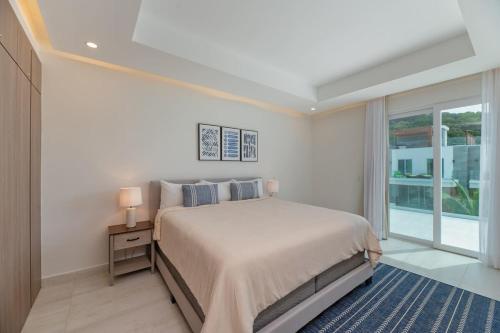 a white bedroom with a large bed and a window at Marlin Villa #10 in West Bay