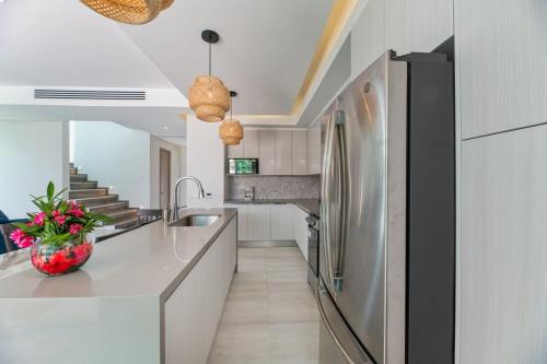 a kitchen with white cabinets and a stainless steel refrigerator at Marlin Villa #10 in West Bay