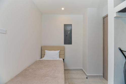 Cama pequeña en habitación con paredes blancas en Marlin Villa #10, en West Bay