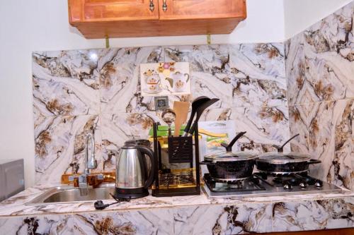 a kitchen counter with a stove and pots and pans at Woody home bonapriso in Douala