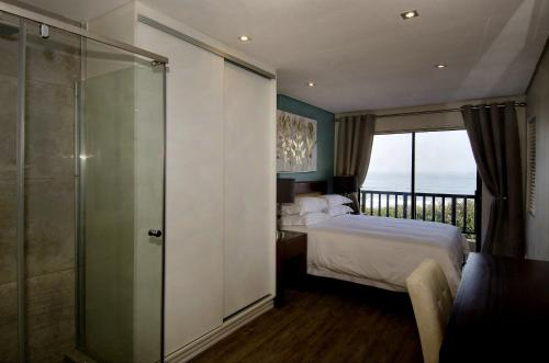a bedroom with a bed and a glass shower at 6 Dolphin Views La Mercy Beachfront in La Mercy
