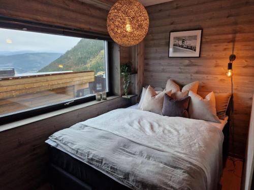 sypialnia z łóżkiem i dużym oknem w obiekcie Ny, eksklusiv hytte til leie på Voss w mieście Skulestadmo
