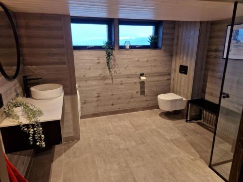 La salle de bains est pourvue de toilettes, d'un lavabo et d'une douche. dans l'établissement Ny, eksklusiv hytte til leie på Voss, à Skulestadmo