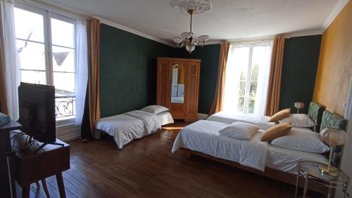 two beds in a room with green walls and windows at Villa du Loir in La Flèche