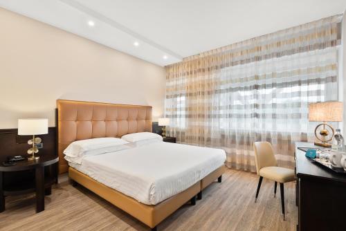 a bedroom with a large bed and a desk and chair at Hotel Excelsior in Marina di Massa