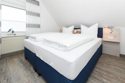 a large white bed with white sheets and pillows at Haus Strandkorb mit Frühstücksoption in Bensersiel