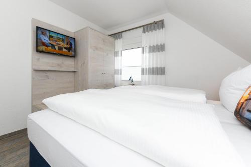 a bedroom with two white beds and a window at Haus Strandkorb mit Frühstücksoption in Bensersiel