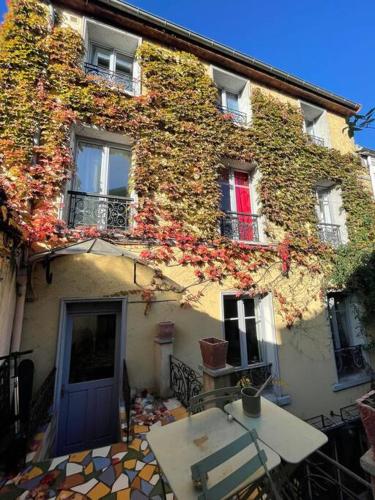 un bâtiment recouvert de lierre et doté d'une table devant lui dans l'établissement Magnifique maison 15 minutes du centre historique de Paris, aux Lilas