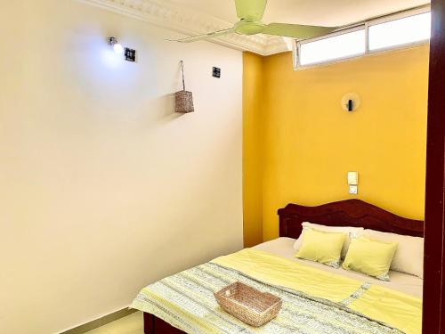 um quarto com uma cama com paredes amarelas e um tecto em Yiri 5 : 2 chambre salon plage em Cotonou