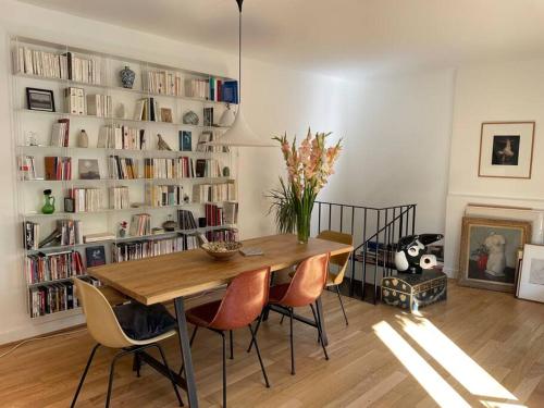 une salle à manger avec une table, des chaises et des étagères dans l'établissement Magnifique maison 15 minutes du centre historique de Paris, aux Lilas