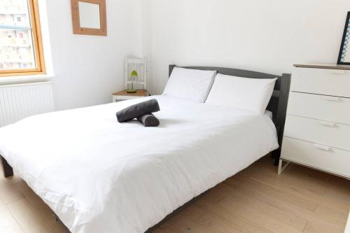 a bedroom with a white bed with a black headboard at Broadway Market Live London in London