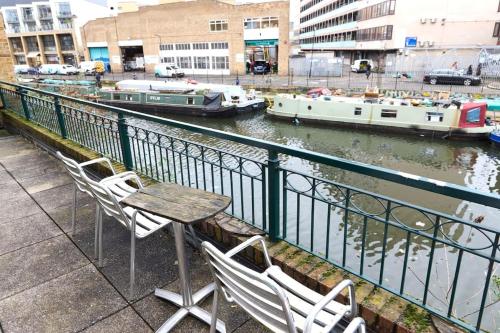 a table and chairs on a balcony with boats in the water at Broadway Market Live London in London