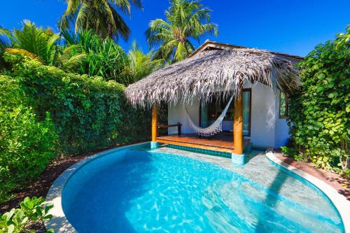 une villa avec un hamac et une piscine dans l'établissement Pousada Samba Pa Ti, à Porto de Pedras